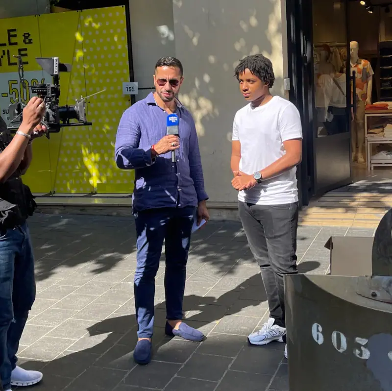 Interview filmée en extérieur entre deux hommes devant une vitrine