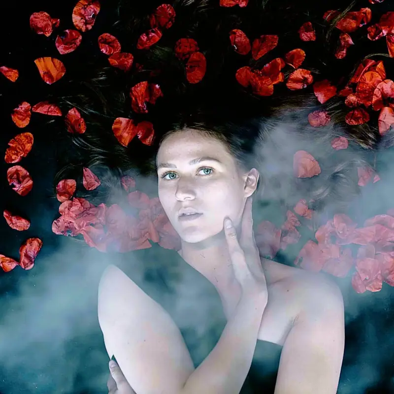 Portrait artistique d'une femme dans la fumée entourée de roses rouges