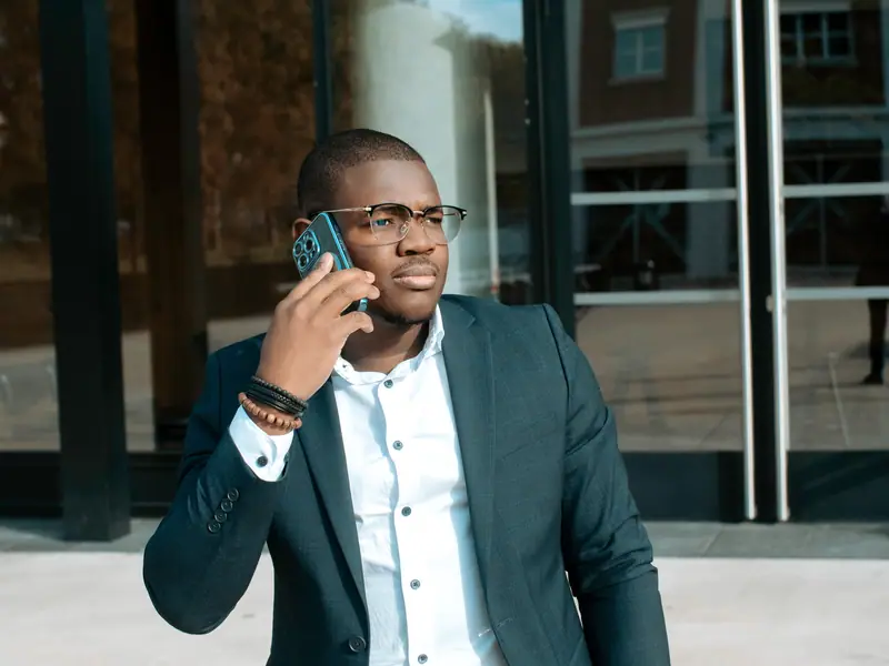 Homme d'affaires au téléphone devant un immeuble de bureaux vitré