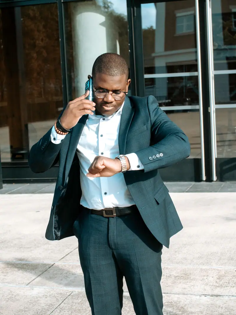 Homme d'affaires en costume regardant sa montre en marchant