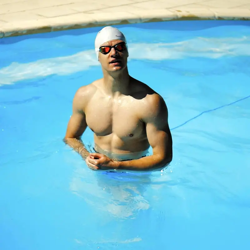 Nageur posant dans une piscine bleue, bonnet blanc