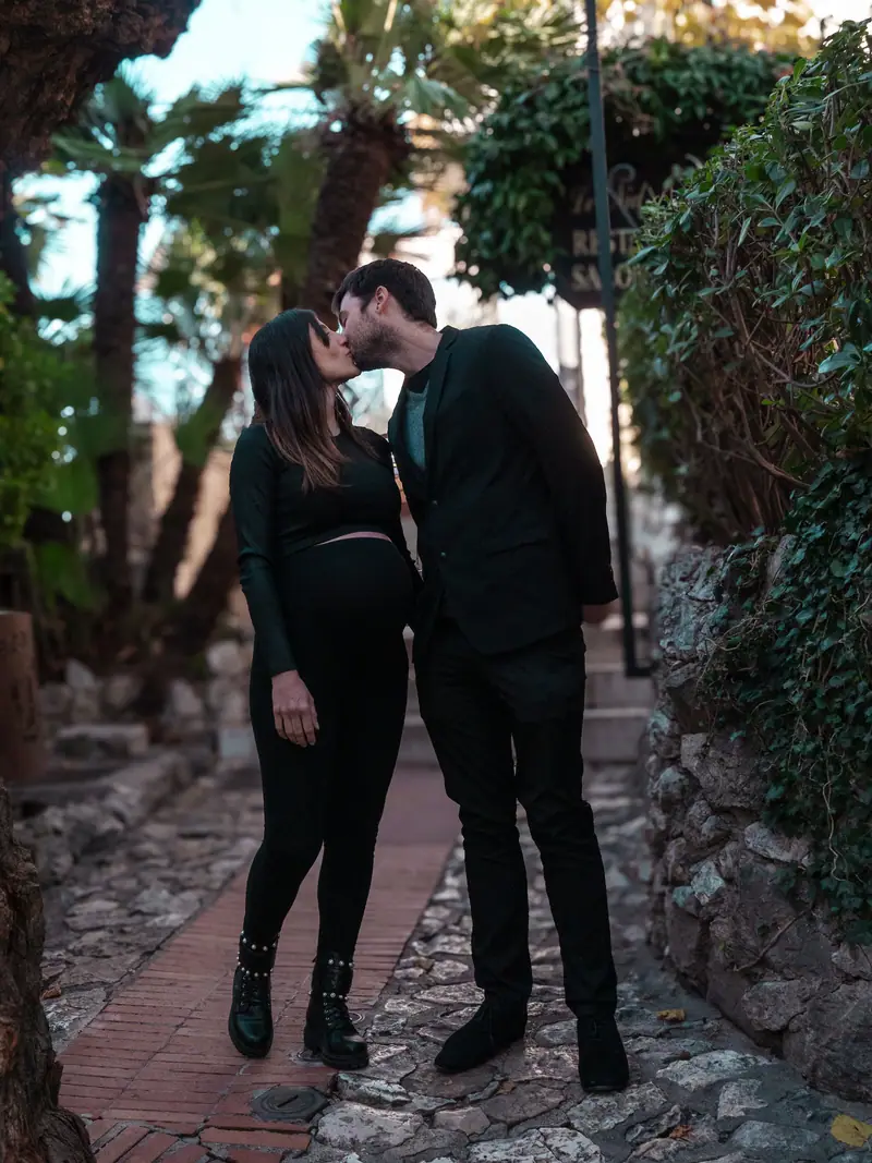 Couple enlacé dans un jardin méditerranéen pendant une séance grossesse