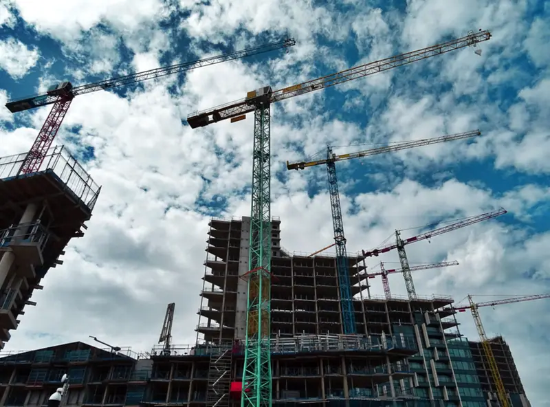 Chantier d’immeuble et grues sous un ciel nuageux