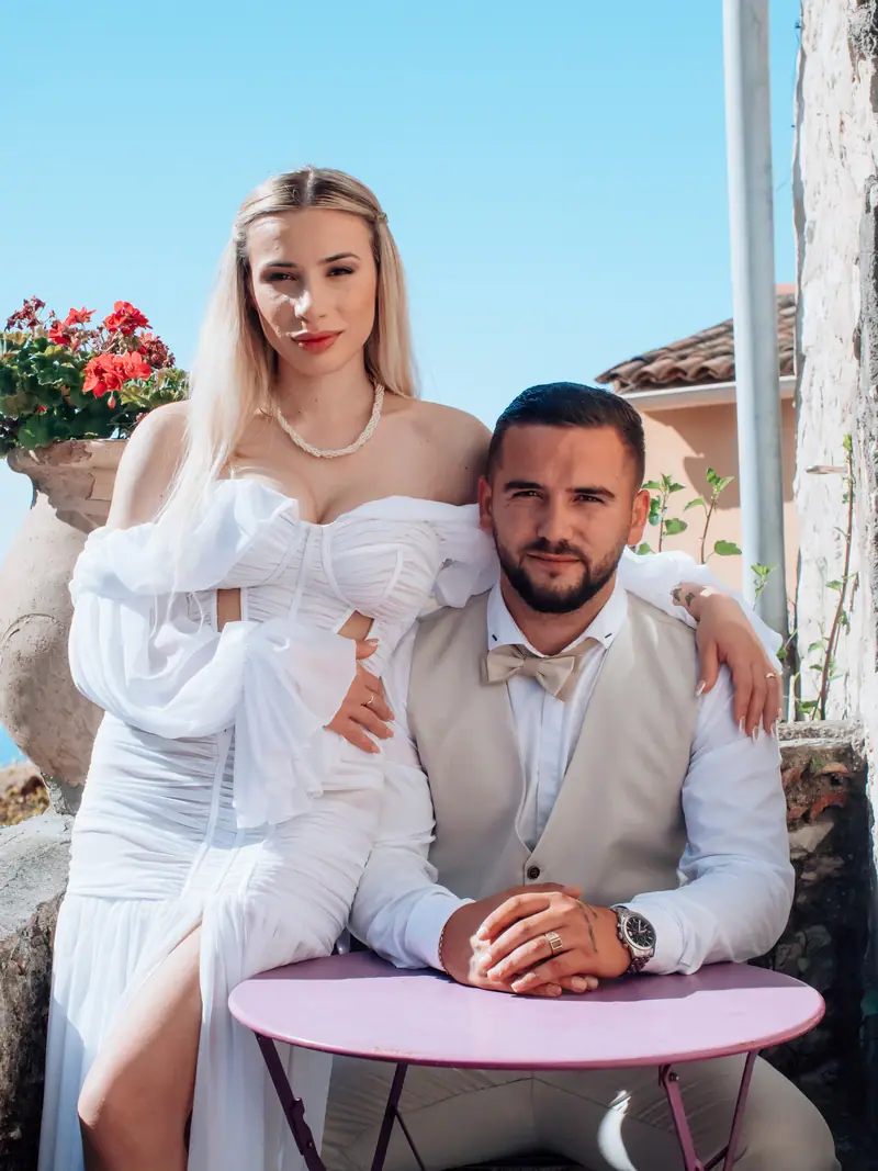 Mariés assis à une table de café rose, la mariée appuyée sur l'épaule du marié