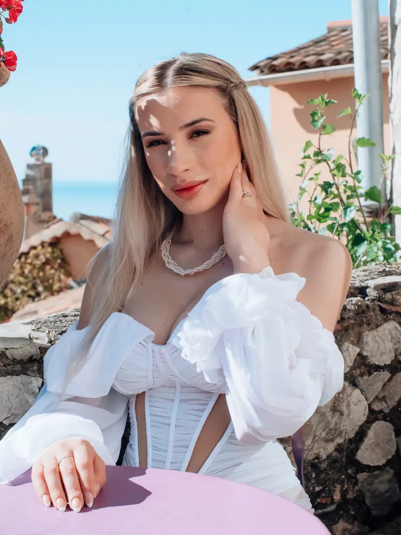 Portrait de la mariée blonde accoudée à une table, regard vers l'objectif