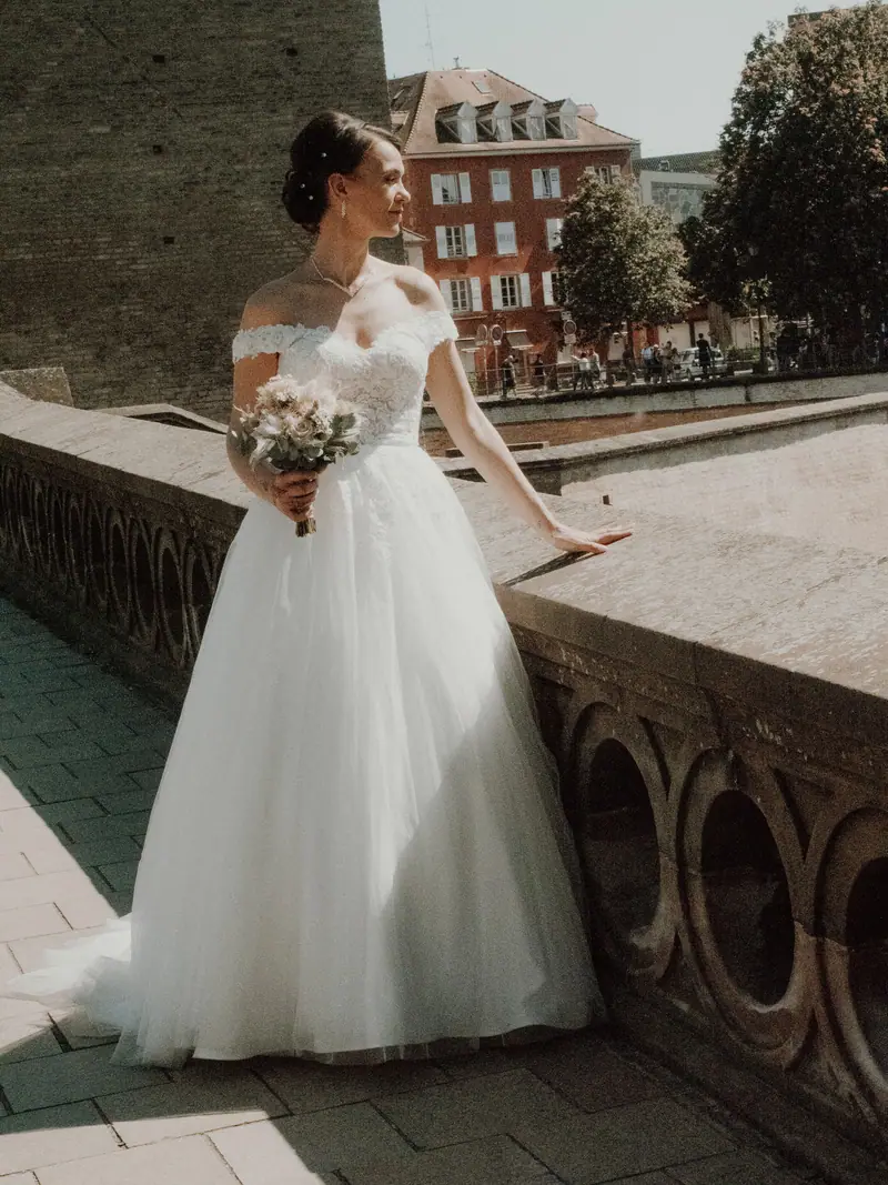 Mariée en robe princesse tenant son bouquet sur une terrasse à balustres