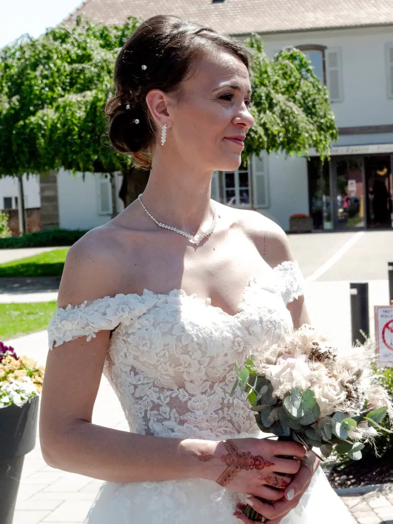 Mariée souriante tenant son bouquet de fleurs pastel dans un jardin