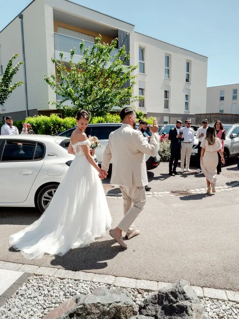 Mariés marchant dans la rue devant leurs invités le jour du mariage
