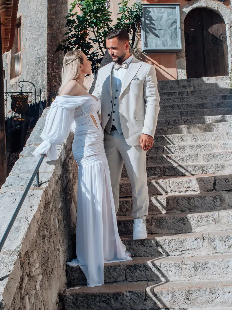 Mariés posant sur un escalier en pierre ancien, la mariée en robe fluide