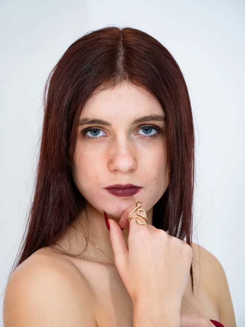 Portrait studio d'une jeune femme aux cheveux auburn, main sous le menton