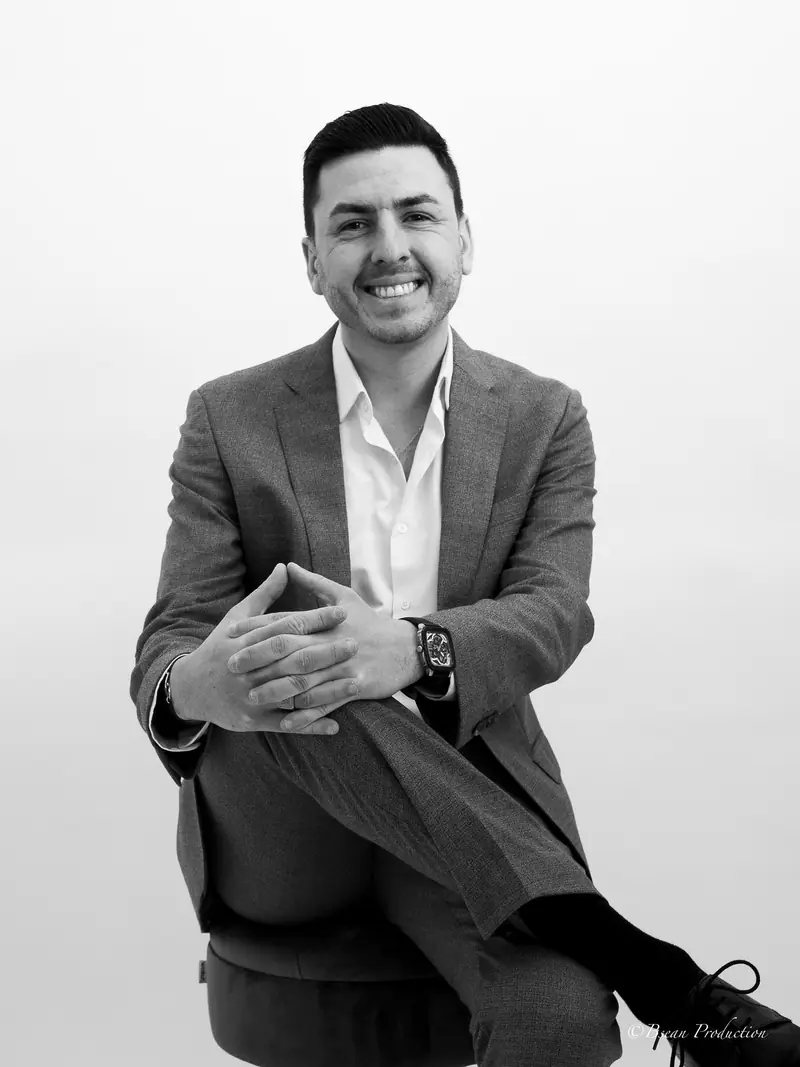 Portrait noir et blanc d'un homme en costume assis, souriant