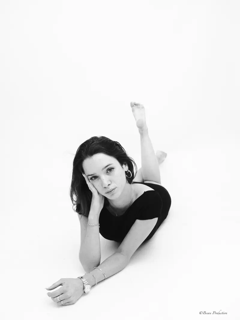 Portrait noir et blanc d'une femme allongée au sol en studio, pose artistique